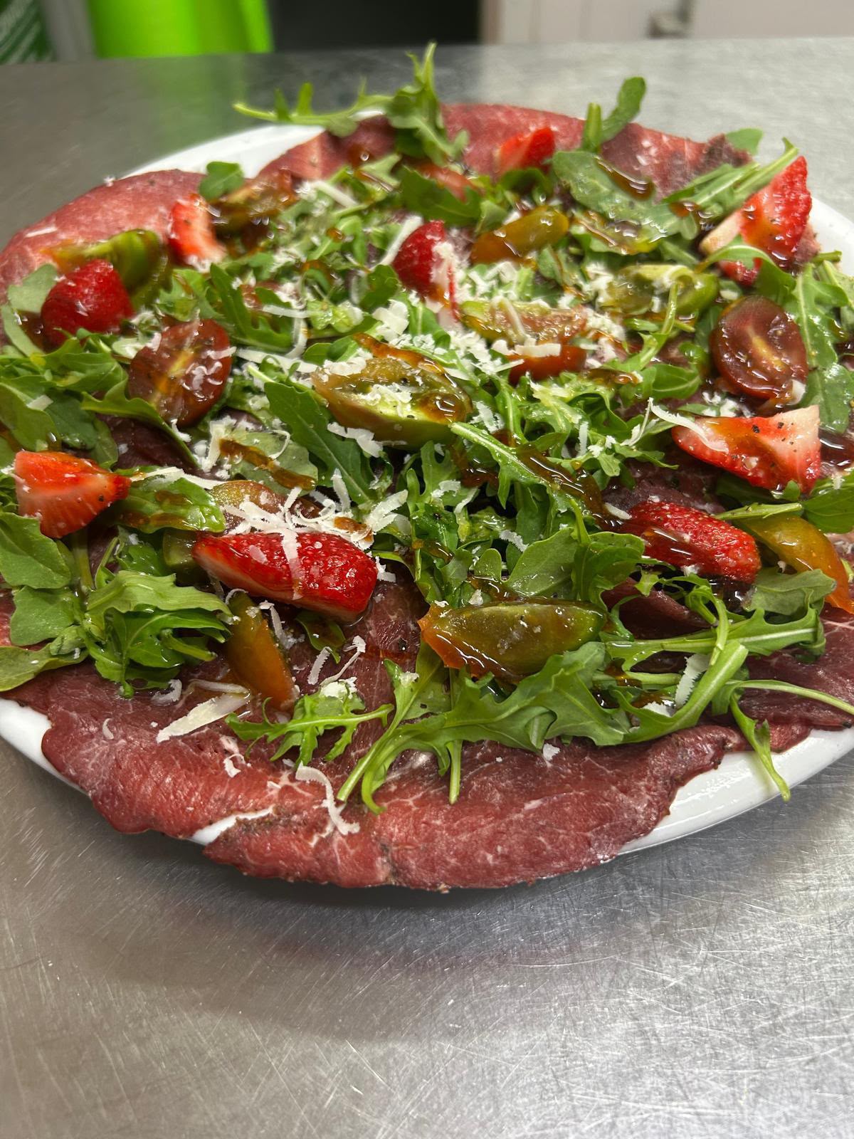Carpaccio de ternera con rúcula, fresas, tomate cherry y parmesano